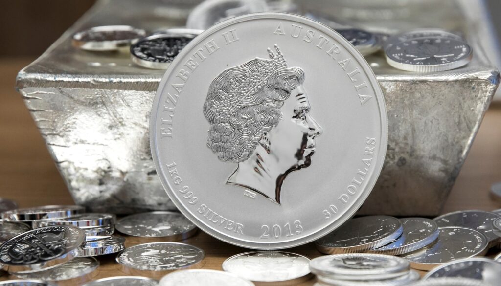 Egy kilogrammos ausztrál ezüstérme Erzsébet királynő arcképével, körülötte kisebb ezüstérmék és ezüstrúd.